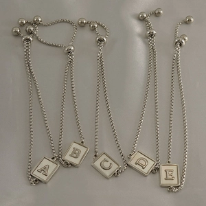 Detail of silver square letter pendants from A to E on adjustable box chain bracelets