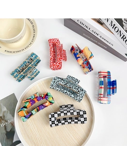 Flat lay of colorful claw clips with leopard and floral prints on a wooden tray