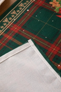 Detail of Christmas table runner fabric showing red green plaid and gingerbread prints