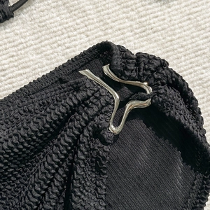 Close-up of black seersucker bikini fabric texture and silver metallic buckle detail