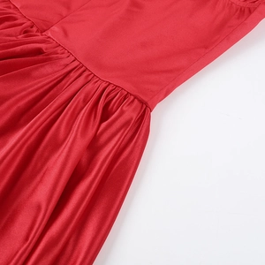 Detailed macro view of the ruched waist design on the red satin bodycon dress
