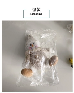 Detail view of plush snowman ornament in clear packaging with pearl buttons and knit hat