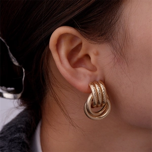 Close-up of model wearing golden multi-layered twisted thread hoop earrings with vintage texture