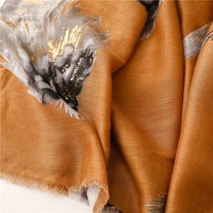 Macro detail of amber shawl featuring gold leaf stamping and soft frayed fringe edges