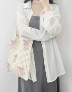 Detail of hand-woven white knit tote bag featuring soft 3D pink bow accents and textures