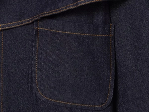 Detailed close-up of dark blue denim jacket with contrast orange stitching on pocket