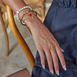 Gold layered jewelry set with pearl bracelet, heart hand chain, and cuff bangle for women