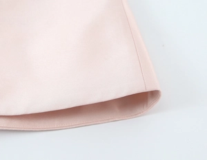 Détail de l'ourlet de la robe en satin rose pâle avec texture lisse et coutures soignées