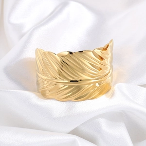 Detail shot of golden feather cuff bracelet with intricate vein texture on white silk