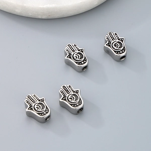 Detailed view of silver Hamsa hand charms with intricate dot patterns for DIY jewelry