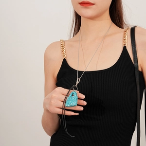 Détail du collier pendentif sac en strass bleu avec chaîne argentée et cordon noir