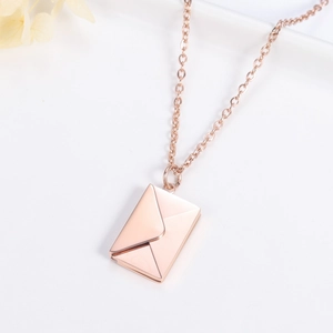 Detail of rose gold envelope pendant on a delicate cross chain with floral background