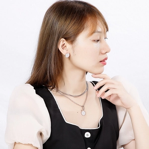 Layered stainless steel necklace and round stud earrings set on a female model
