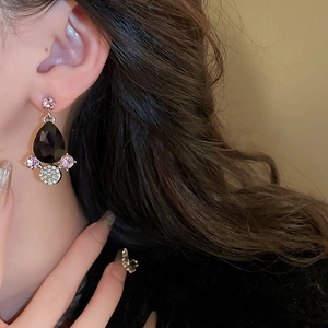 Macro shot of silver drop earrings with black and pink gems worn by a model