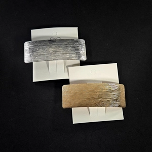 Detailed view of rectangular brushed metal hair clips in silver and gold finishes