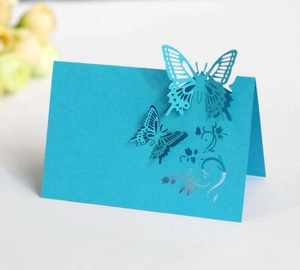 Detail of laser-cut butterfly wedding place card in light blue with intricate hollow design