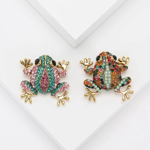 Macro shot of luxury gold frog brooches with colorful rhinestones on a white stand