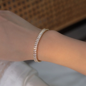 Bracelet élégant en plaqué or avec zircons rectangulaires sur le poignet d'un modèle