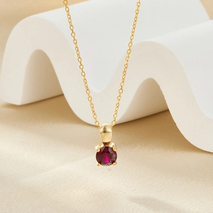 Detail view of a 925 sterling silver gold necklace featuring a round red gemstone pendant
