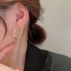 Elegant gold twisted square hoop earrings with sparkling zircons worn by a female model