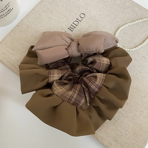 Macro detail of checkered fabric bow scrunchie with soft brown and beige layers