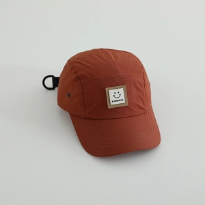 Detail view of the orange 5-panel outdoor cap with a smile face patch and D-ring buckle