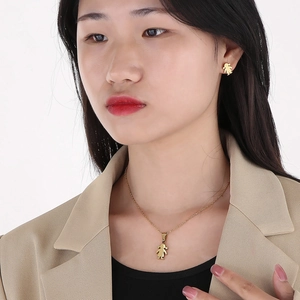 Detail shot of a minimalist gold girl character pendant necklace and stud earrings set