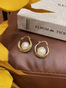 Détail macro de boucles d'oreilles en perles baroques plaquées or 16 carats sur cuir
