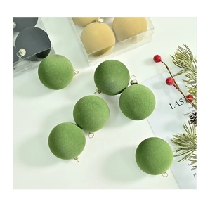 Detailed view of 6cm flocked Christmas balls in green and gold matte velvet texture