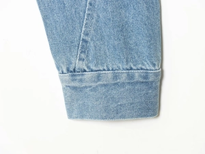 Detalle del puño de mezclilla azul claro que muestra las costuras y la textura