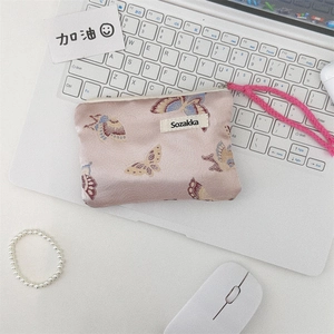 Detail of floral jacquard butterfly bag with pink woven strap on a laptop keyboard