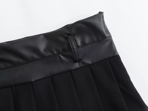 Detail of black pleated skirt featuring high-quality faux leather waist texture and seams