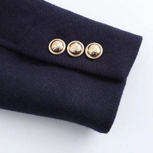 Detail of wool blend coat cuff with three gold shield-embossed decorative metal buttons