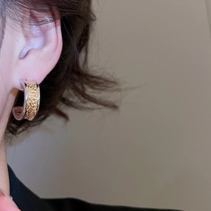 Detailed close-up of C-shaped two-tone gold and silver earrings worn by a model