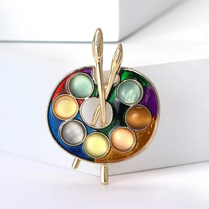 Detail of artist palette brooch with colorful enamel, cat eye stones and golden brushes