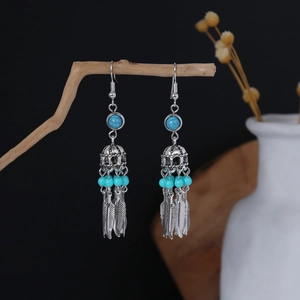 Detail of bohemian drop earrings with turquoise beads and antique silver feather pendants