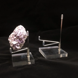 Detailed view of acrylic crystal display stand with adjustable metal arms on black background