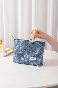 Macro detail of blue paisley jacquard fabric and silver zipper on the makeup bag