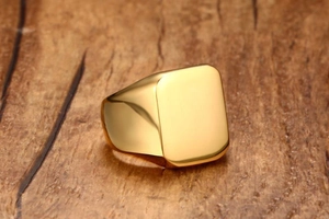 Macro shot of gold square signet ring for men on rustic wood background with polished finish