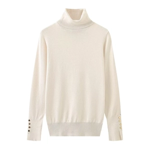 Close-up of decorative gold buttons on the cuffs of a beige turtleneck knit sweater