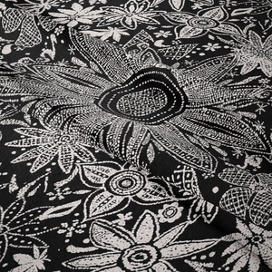 Dettaglio ravvicinato di arazzo boho con motivi floreali bianchi e trama fine del tessuto