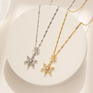 Close-up of gold and silver snowflake necklaces with zircons and pearls on a white base