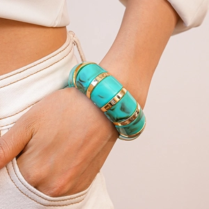 Detail of turquoise marble resin links and gold metal rings on a woman's wrist