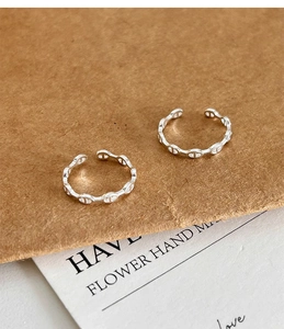 Macro shot of silver pig-nose open rings on artistic brown paper and white cards