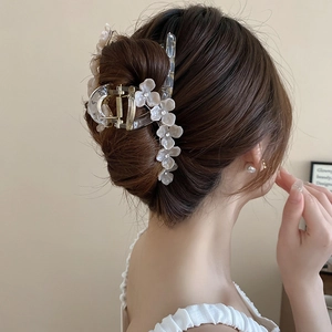 Détail d'une pince à cheveux avec fleurs en résine blanche et strass sur les cheveux