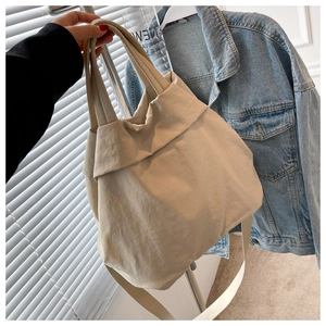 Detailed close-up of a beige lightweight nylon tote bag with wide straps and long shoulder strap
