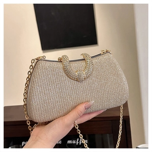 Detail of gold glitter clutch bag with U-shaped crystal buckle and metal chain strap
