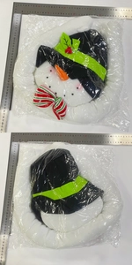 Detail of Christmas snowman plush topper with striped bow and carrot nose in packaging