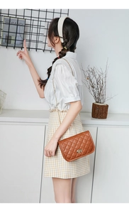 Detailed view of brown quilted crossbody bag with gold chain strap worn by a model