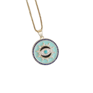 Macro detail of 18K gold evil eye necklace with turquoise enamel and blue zircon stones
